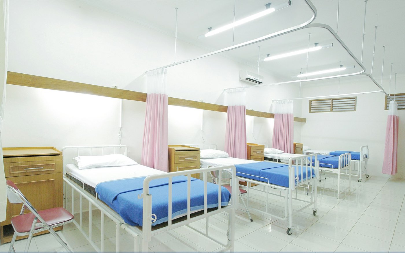 A hospital ward with rows of beds and medical equipment